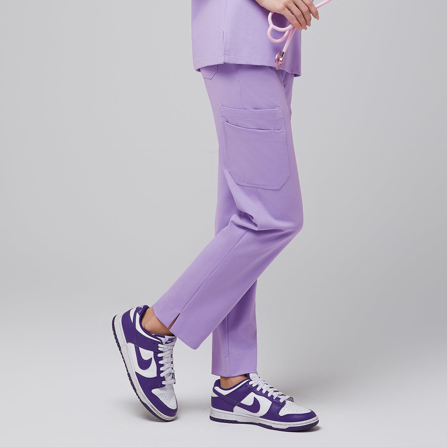 Side view of lavender scrub pants with side pocket and split hem, paired with purple sneakers,Lavender