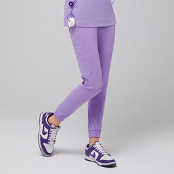 Image of Female wearing lavender jogger scrub pants with side pockets, paired with purple and white sneakers,Lavender