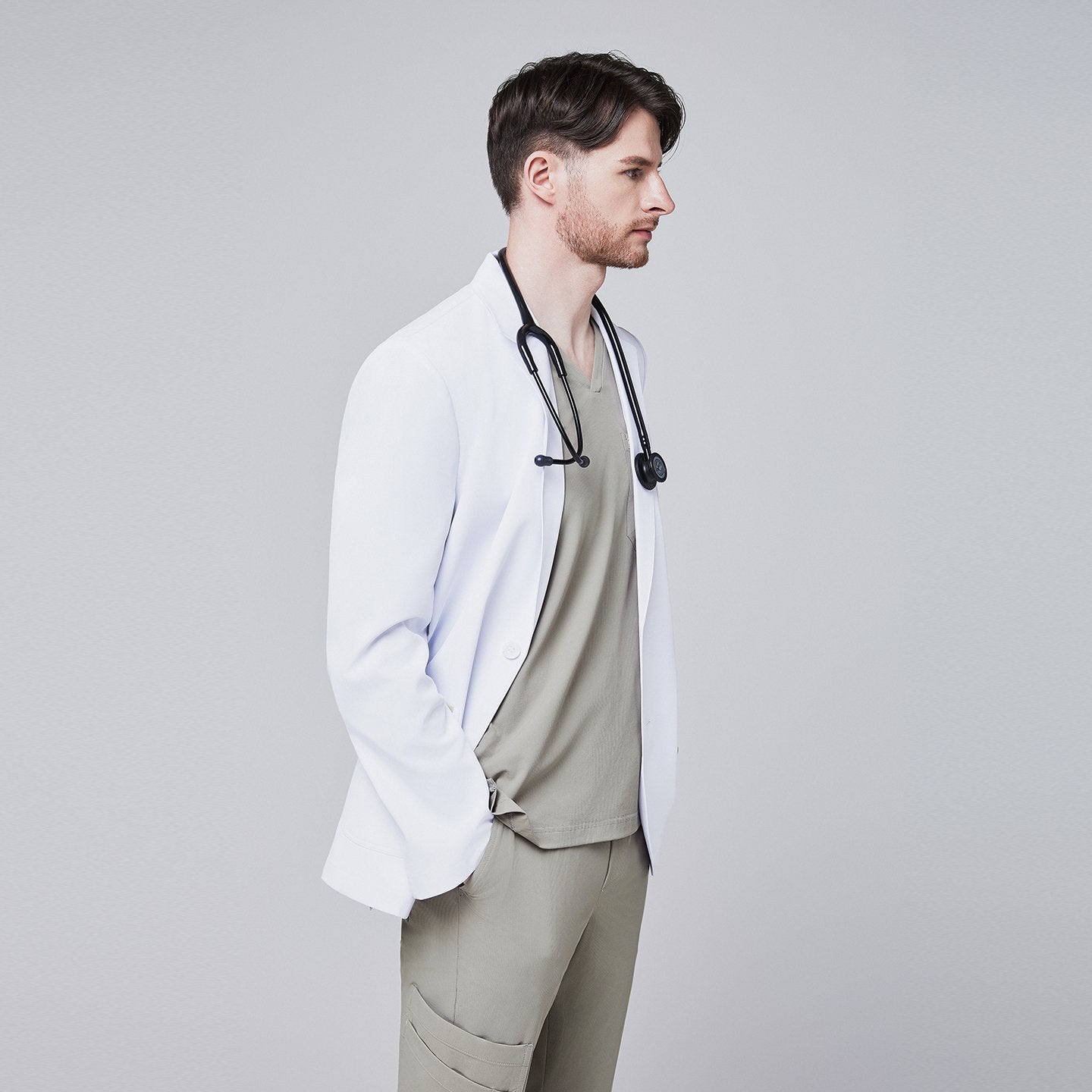 Side view of a man wearing a short white lab coat (LCM-01) over a Sand Khaki Single Pocket Scrub Top and Sand Khaki StretchFit Jogger Scrub Pants, with a stethoscope around his neck,White