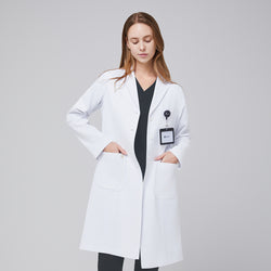 Image of A woman wearing a long white lab coat (LCW-04) over a Deep Gray Single Pocket Scrub Top and Deep Gray Zipper Pocket Jogger Scrub Pants, with an ID badge on the coat,White