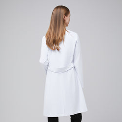 Image of Back view of a woman wearing a long white lab coat (LCW-04) with a buttoned back belt detail, over Eco Navy scrubs,White