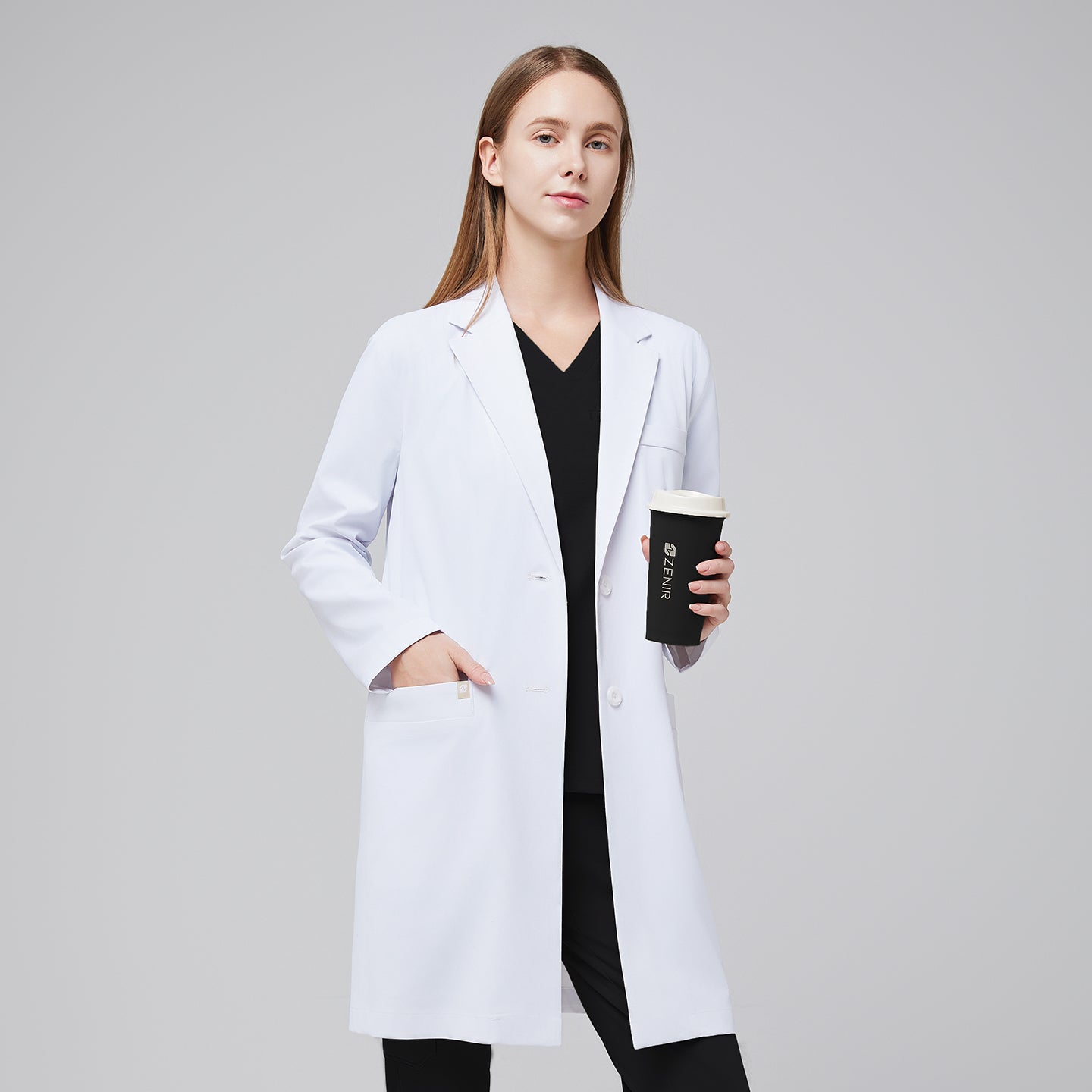 A woman wearing a white long lab coat (LCW-10) over black scrubs, holding a coffee cup,White






