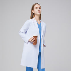 Image of A woman wearing a white women’s Long Lab Coat LCW-10 over a Sky Blue Soft Stretch Scrub Top and Sky Blue Split Hem Scrub Pants, holding a coffee cup,White