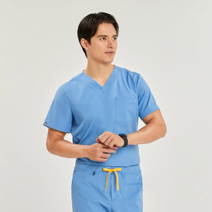 Male model wearing a scrub top with a chest pocket, paired with matching scrub pants with a drawstring, looking to the side,Ceil Blue