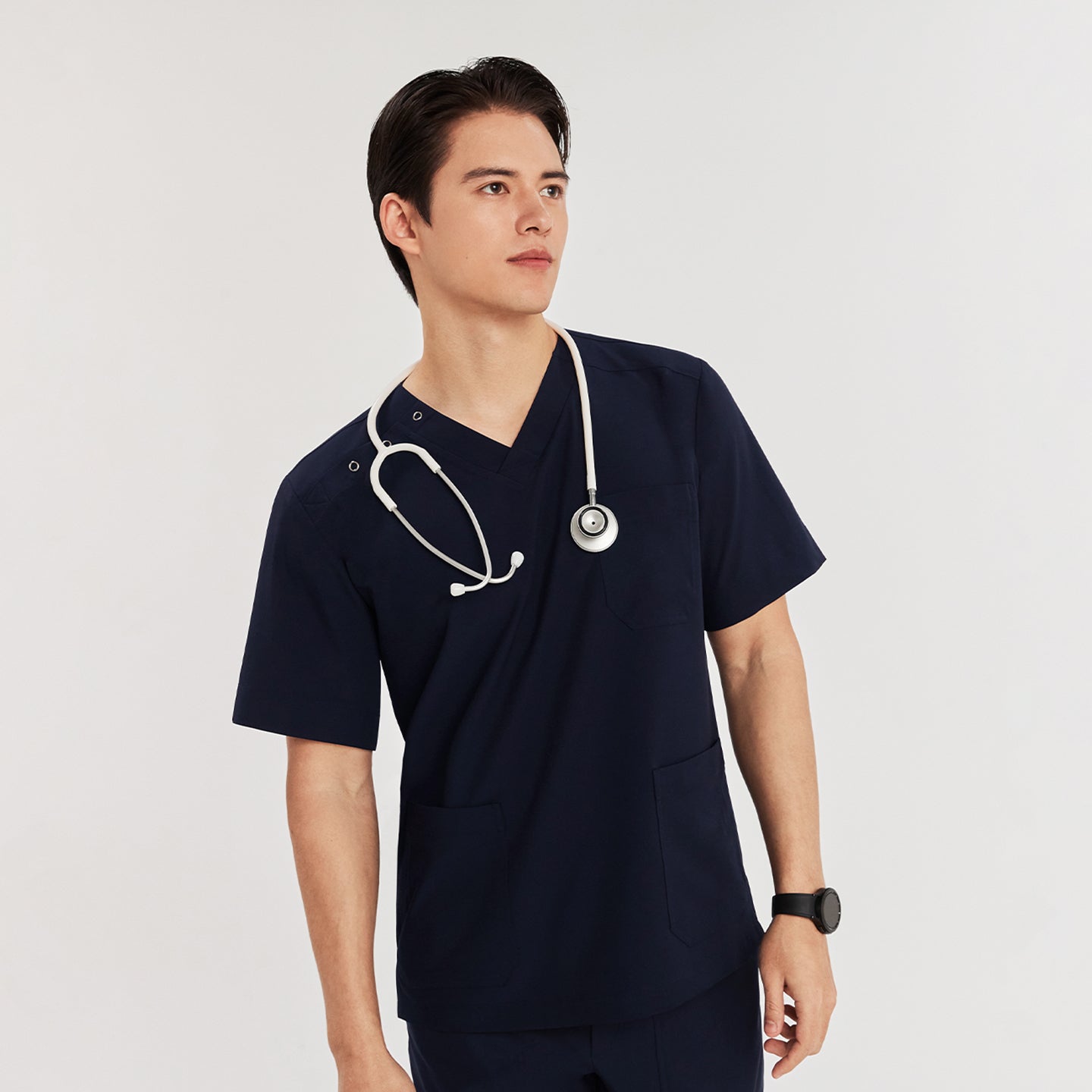 Man wearing a scrub top with three-button shoulder detail and a stethoscope around his neck, standing with a confident pose,Navy