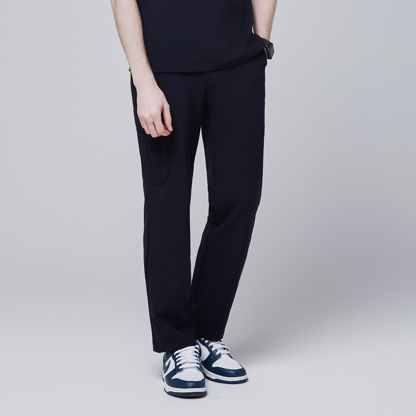 Male model wearing midnight navy relaxed-fit scrub pants with a side pocket, standing in a slightly angled pose, highlighting the front side of the pants, against a plain background,Midnigh Navy