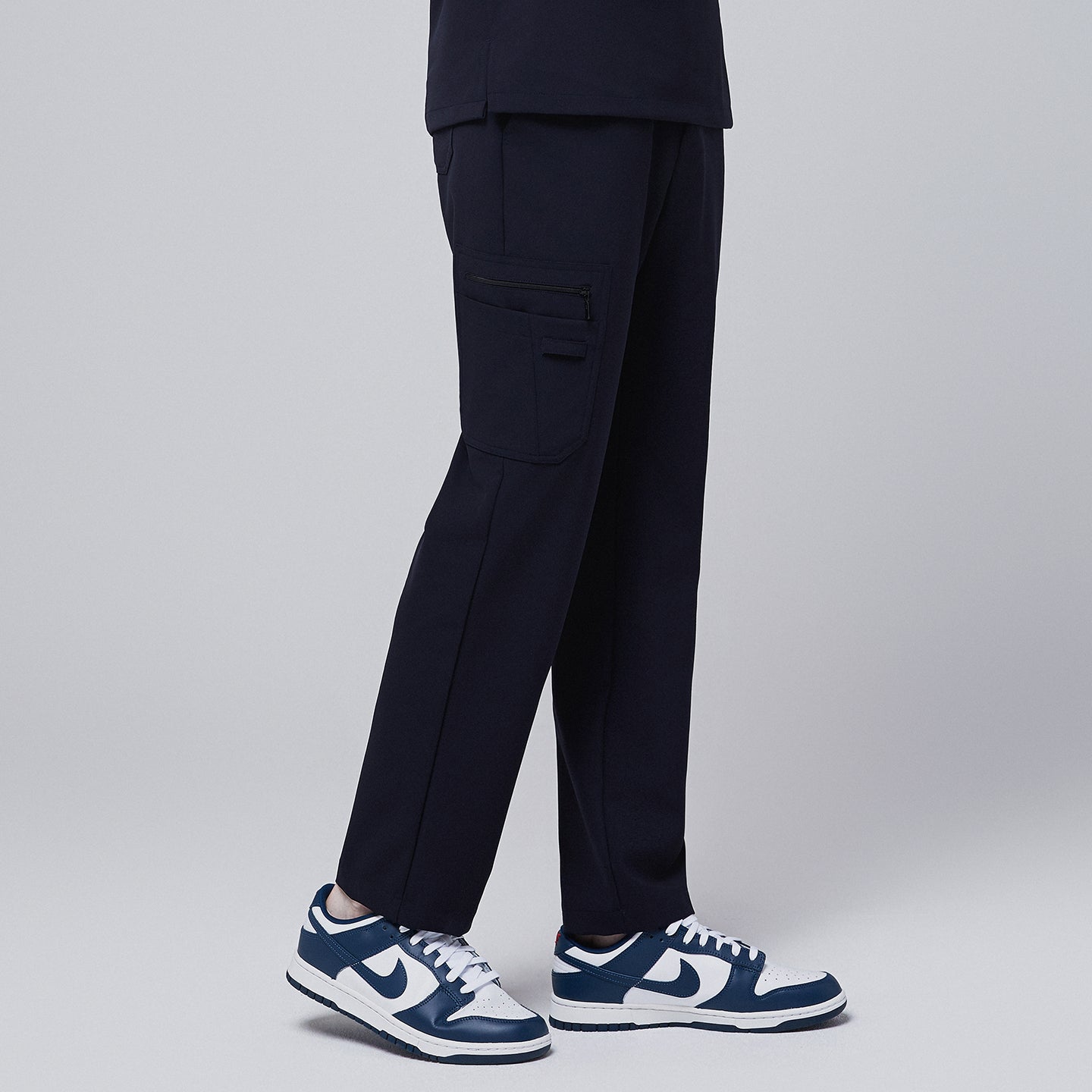 Male model displaying the side view of midnight navy relaxed-fit scrub pants with a functional side pocket, highlighting the pant's design details and pocket structure,Midnigh Navy