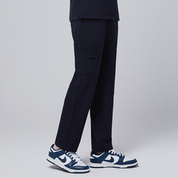 Image of Male model displaying the side view of midnight navy relaxed-fit scrub pants with a functional side pocket, highlighting the pant's design details and pocket structure,Midnigh Navy