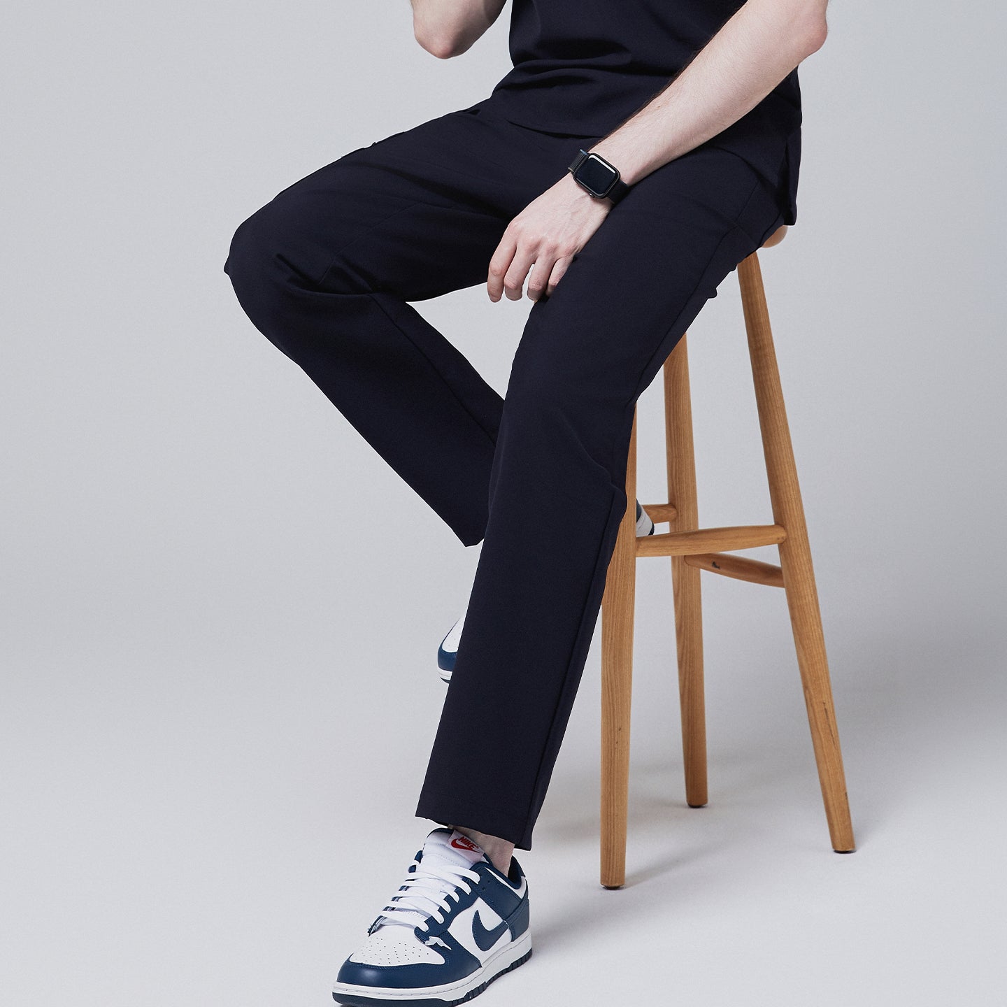 Male model seated on a wooden stool, wearing midnight navy relaxed-fit scrub pants, showcasing the fit and comfort while sitting,Midnigh Navy