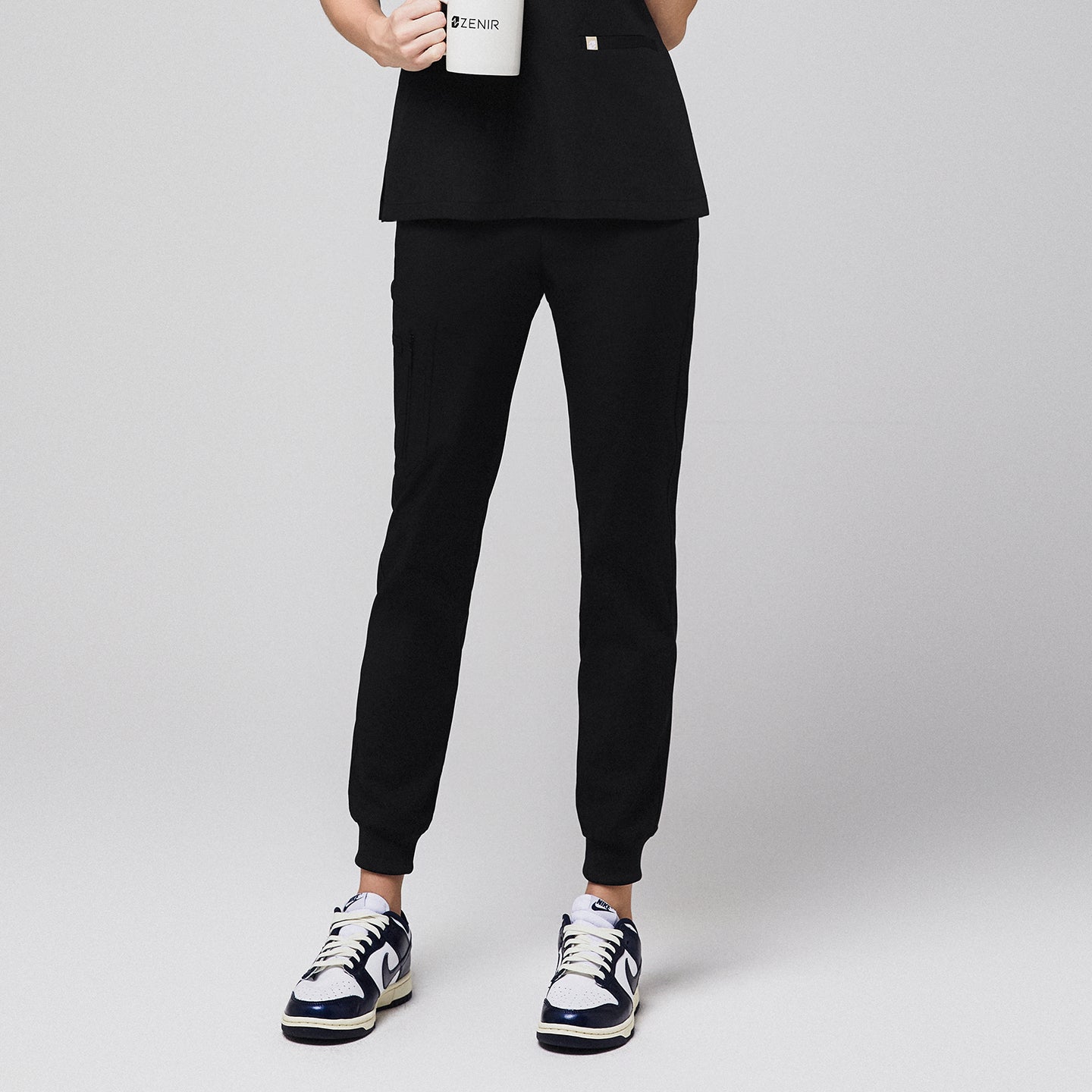 Jogger-style scrub pants with side pocket worn by a medical professional holding a mug,Midnight Black