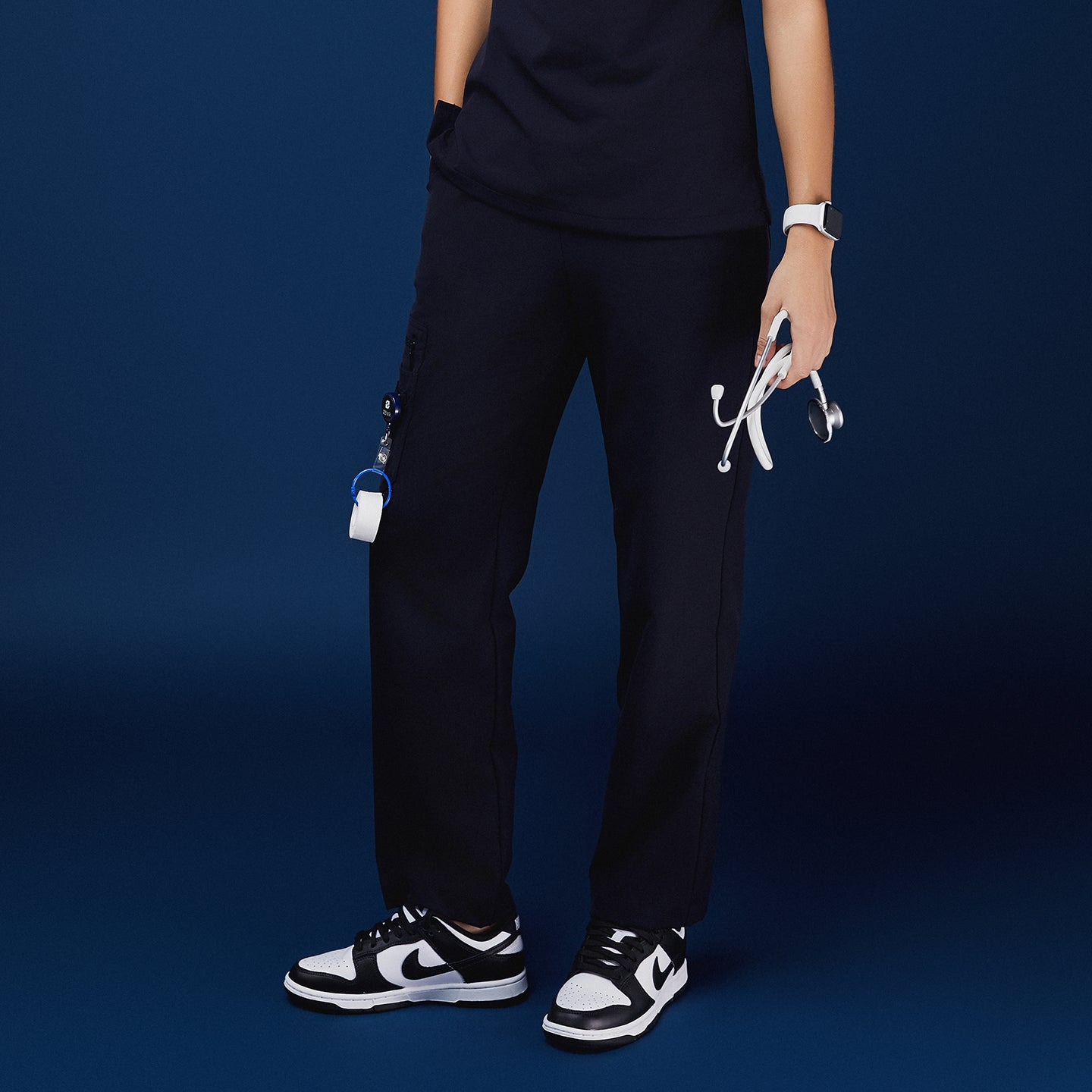 Navy utility scrub pants with functional side pockets, styled with a navy top, stethoscope, and black-and-white sneakers,Midnight Navy