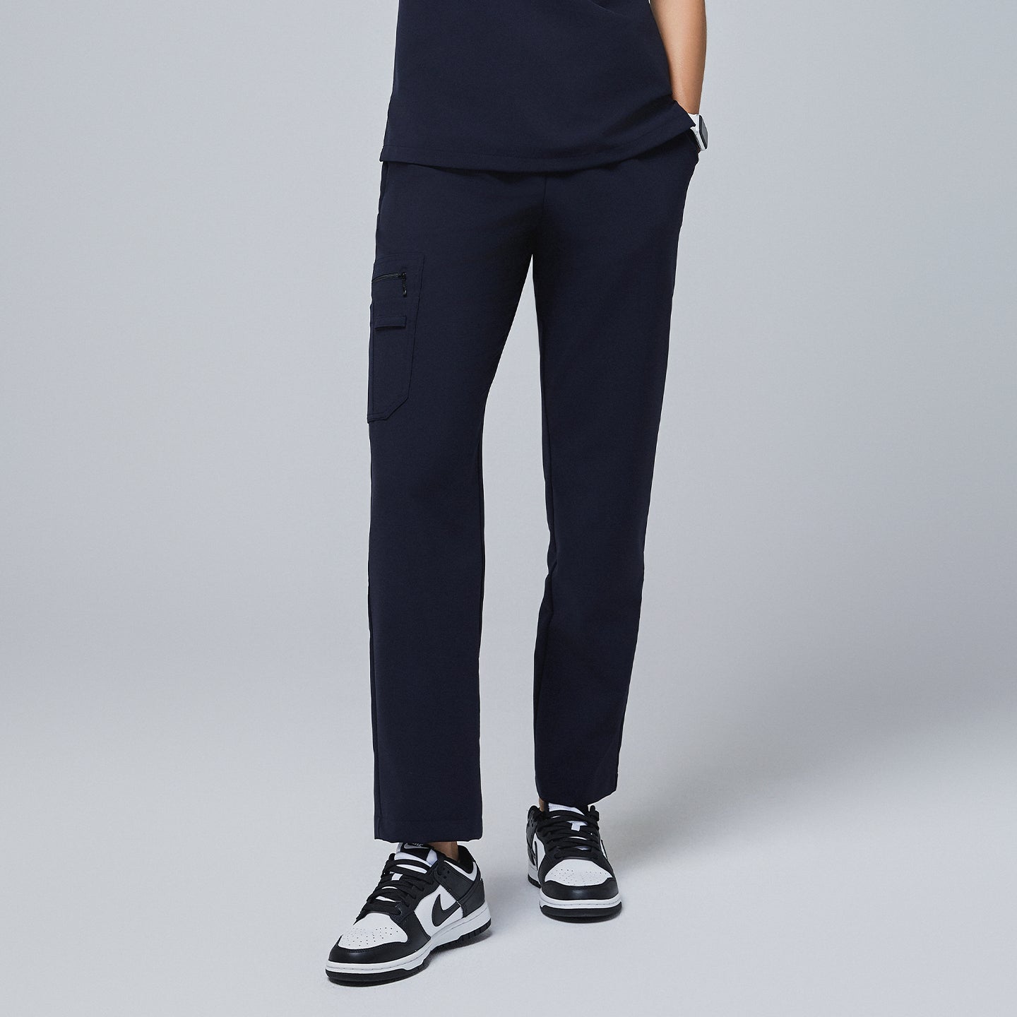 Navy utility scrub pants with a functional side pocket and a sleek fit, paired with black-and-white sneakers,Midnight Navy