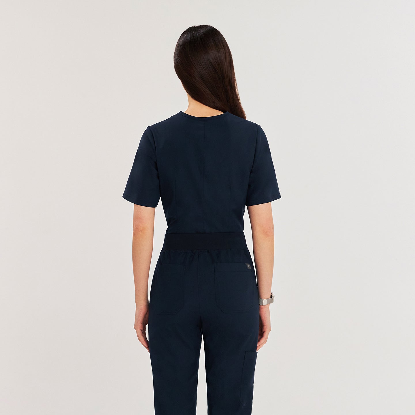 Female model wearing a navy 3-pocket scrub top and matching pants, showcasing a sleek and professional medical uniform,Navy