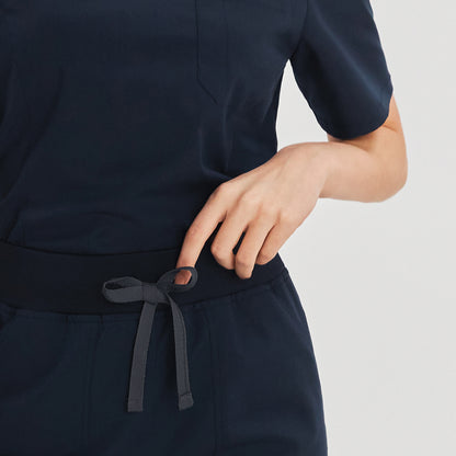 Close-up view of a drawstring detail on the scrub pants with a tied bow, and a partial view of the scrub top's chest pocket, showcasing the design and fit, Navy