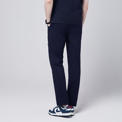 Image of man wearing Zenir navy 8-pocket straight scrub pants, rear view showcasing pocket details, paired with blue and white sneakers,Navy