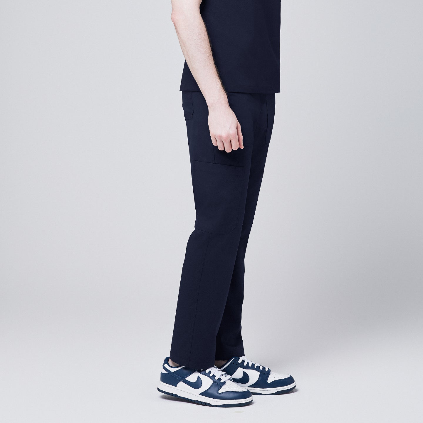 Close-up of Zenir navy 8-pocket straight scrub pants paired with blue and white sneakers,Navy