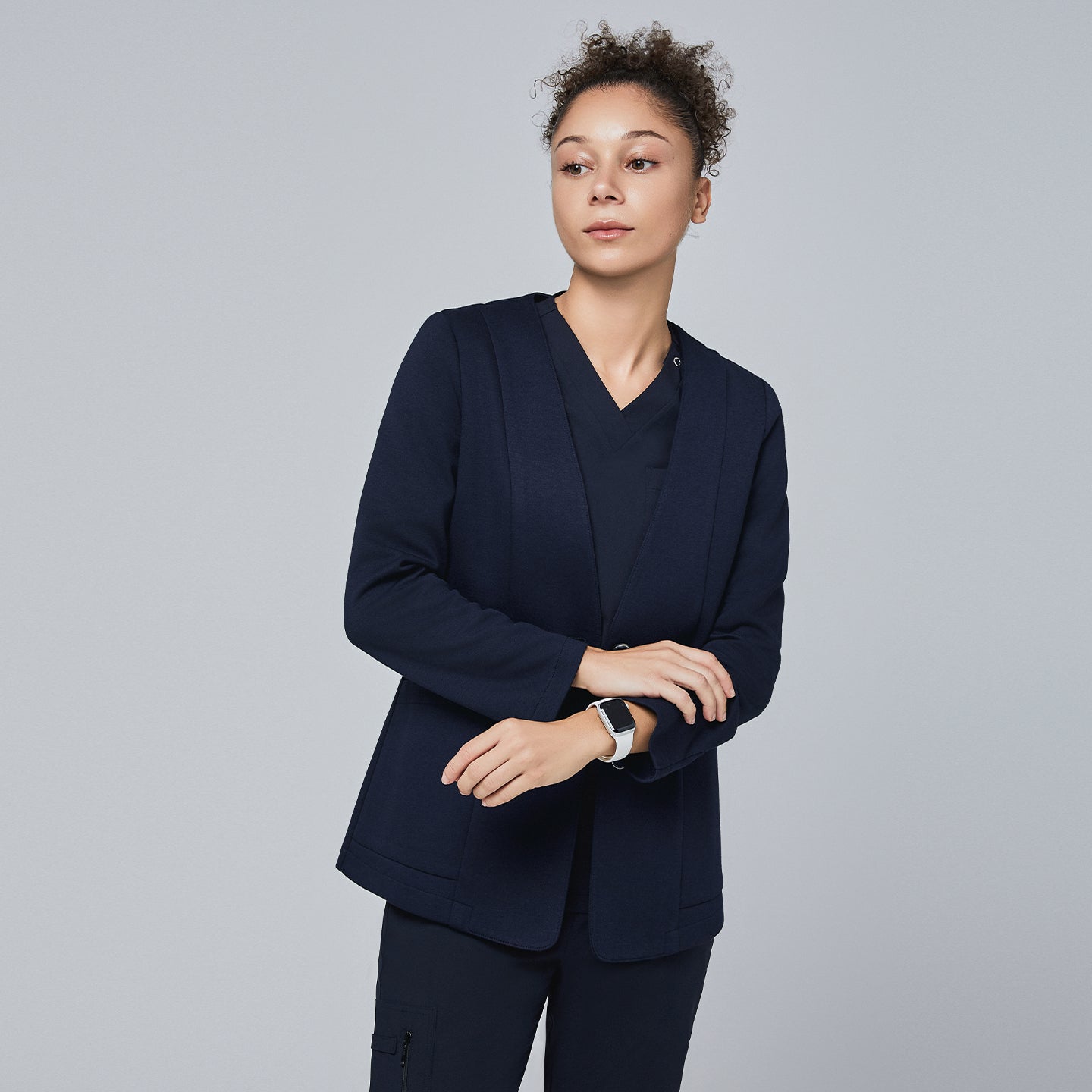 Woman wearing a navy comfort cardigan layered over a V-neck scrub top, accessorized with a smartwatch, for a professional appearance,Navy