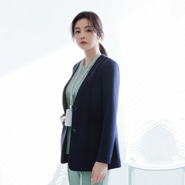 Woman in navy Zenir jacket over light green top and pants, standing and looking at the camera, half-side view,Navy