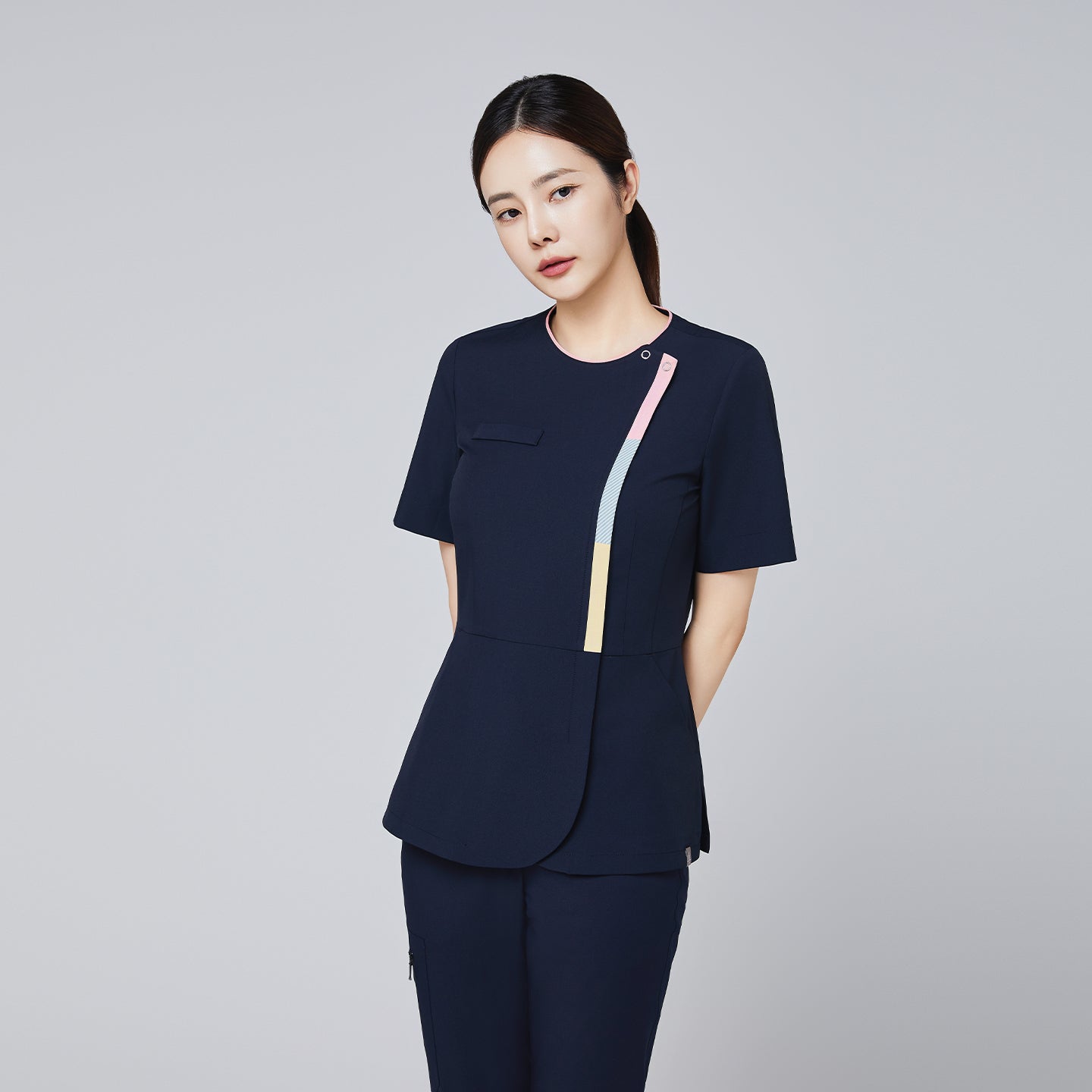 Navy scrub top with gradient front zipper detail and a tailored fit, modeled by a woman in a professional pose,Navy