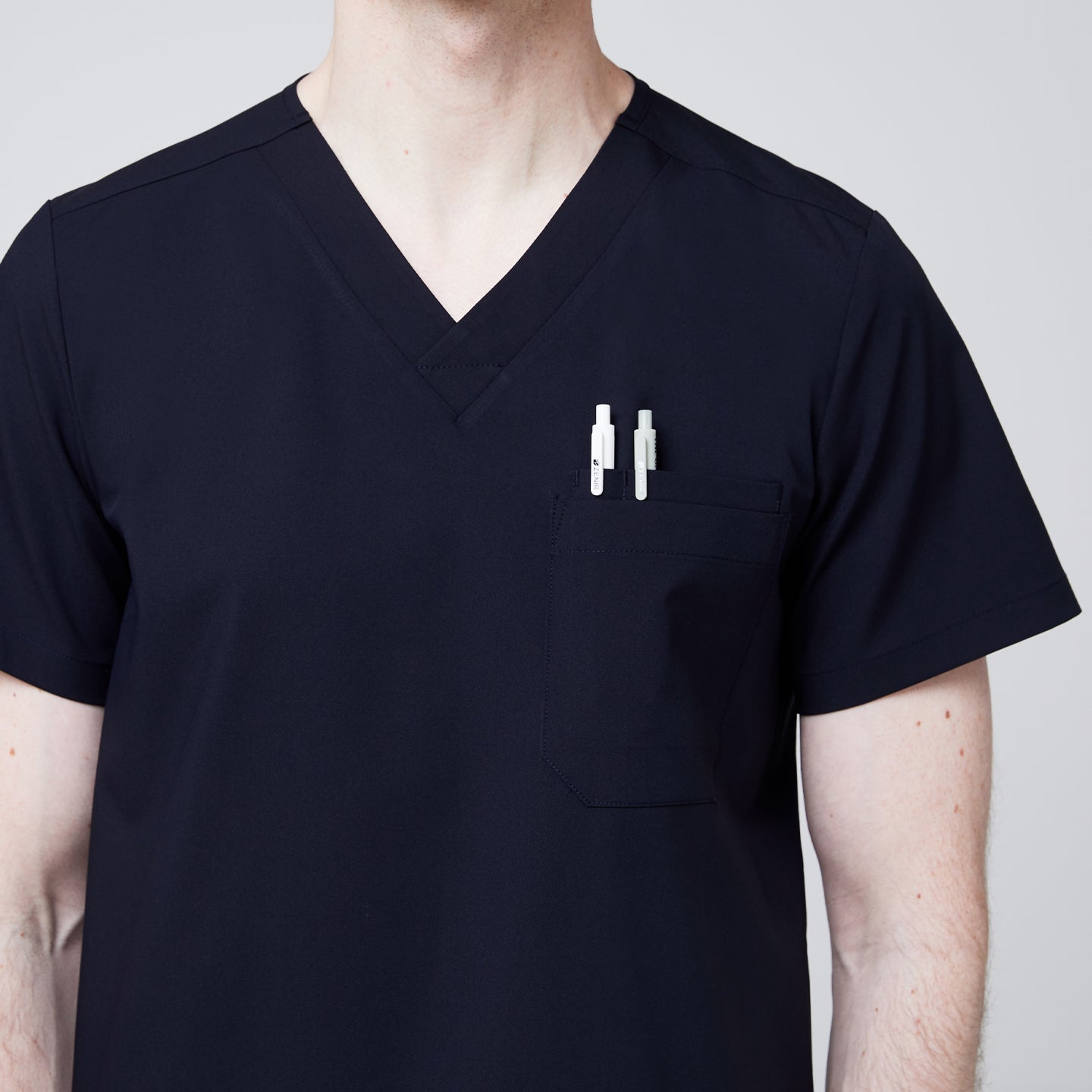 Navy V-neck scrub top with chest pocket holding two pens, worn by male healthcare professional,Navy