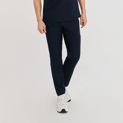 Front view of a model wearing navy blue straight scrub pants with zipper details and a matching top, paired with light-colored athletic shoes,Navy