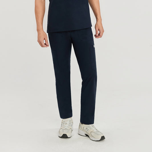 Front view of a model in navy blue straight scrub pants with zipper details, matching top, and light-colored sneakers,Navy