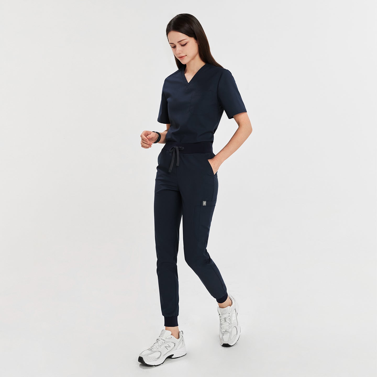  Full-body view of a model in navy jogger scrub pants with a drawstring waist, matching scrub top, and white sneakers,Navy