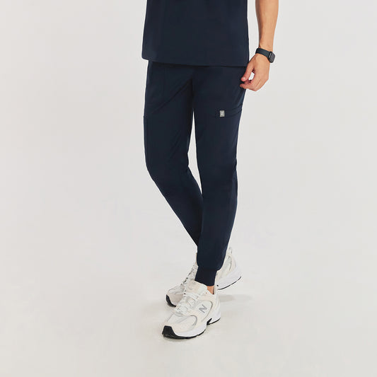 Jogger-style scrub pants with elastic cuffs and a side pocket, worn with white New Balance sneakers,Navy
