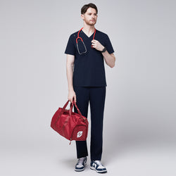 Image of Full-body view of a man wearing a navy scrub top with button details and matching pants, holding a red duffle bag and a stethoscope, exuding a professional and functional look,Eco Navy