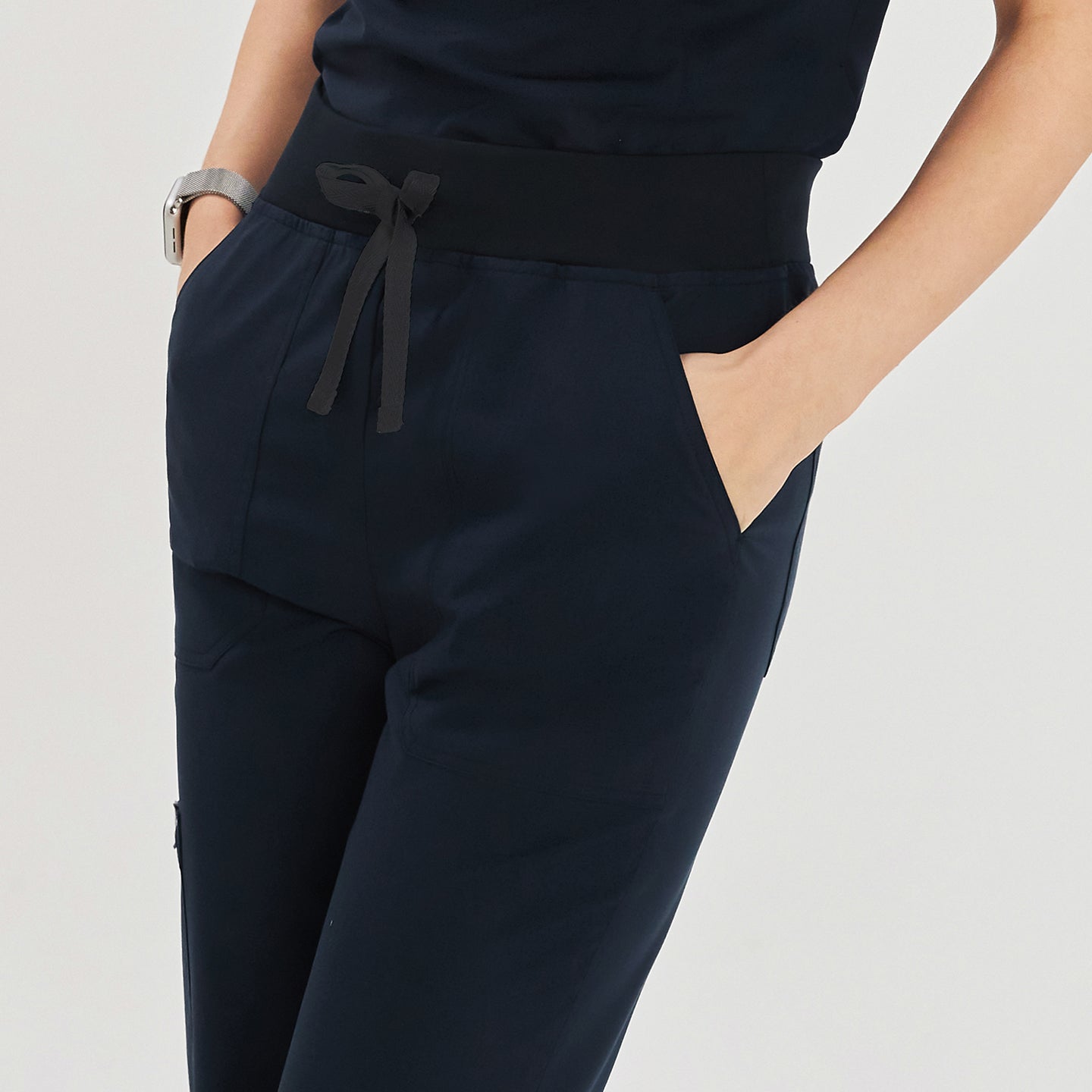 Close-up of model in navy jogger scrub pants showing the elastic waistband with a drawstring and side pockets,Navy