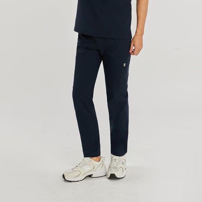 Side view of a model wearing navy blue zipper straight scrub pants with zipper details and a matching top, paired with white athletic shoes,Navy