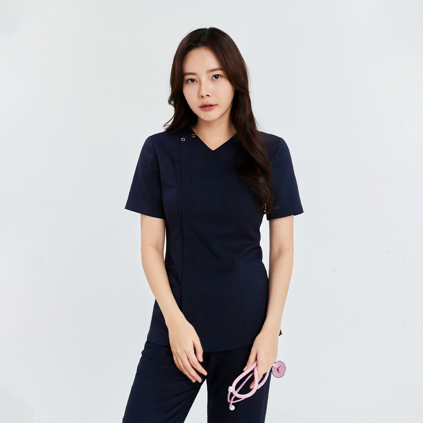  Woman wearing a navy front zipper scrub top with matching straight-leg pants, holding a pink stethoscope,Navy