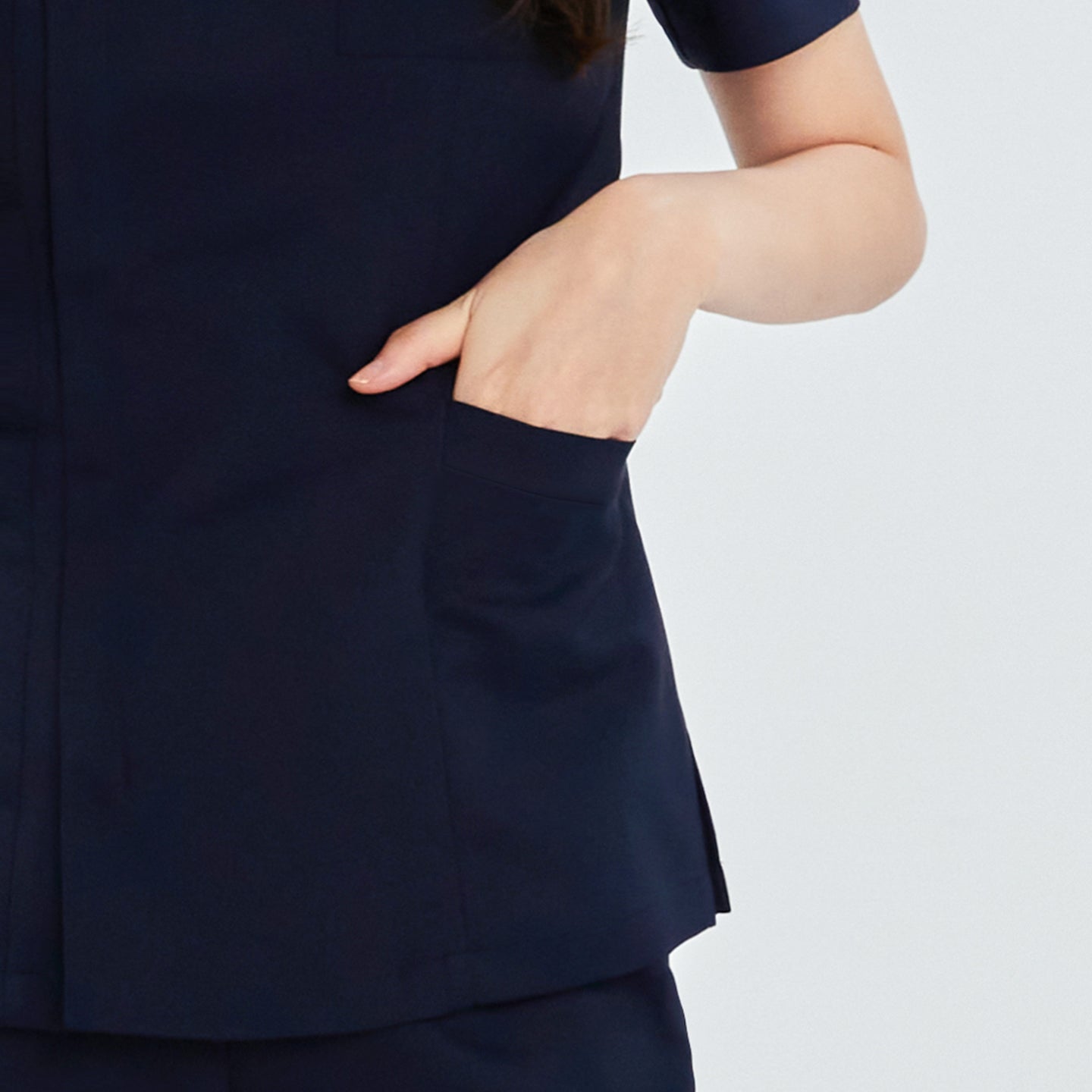 Close-up of navy front zipper scrub top showing a hand in one of the side patch pockets,Navy