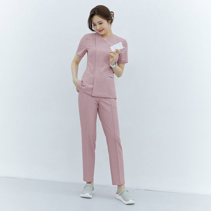 Woman in soft pink front zipper scrub top and straight-leg pants, holding an ID, standing in a clean, minimalist setting,Soft Pink