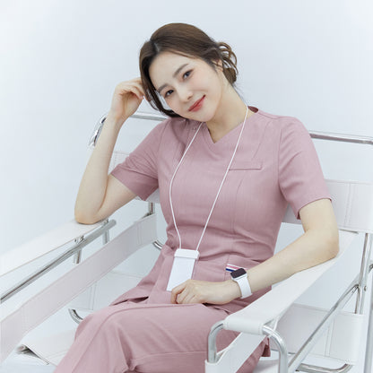 Woman smiling while sitting in a chair, wearing a Zenir soft pink front zipper scrub top and matching pants,Soft Pink