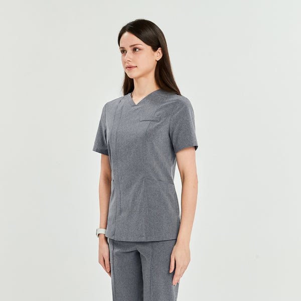 Woman wearing Zenir's 3-Pocket Scrub Top with front zipper, shown from the side. The top features a tailored fit and functional design for comfort and style,Soft Gray