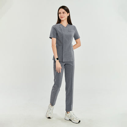 Woman in soft gray Zenir front zipper scrub top with matching pants, standing side view. Professional and comfortable fit,Soft Gray