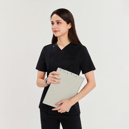 Woman in a black front zipper scrub top and straight-leg pants, holding a clipboard, looking to the side,Black