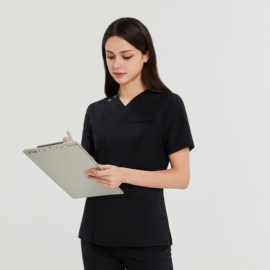 Woman in a black front zipper scrub top with matching straight-leg pants, holding a clipboard and pen,Black