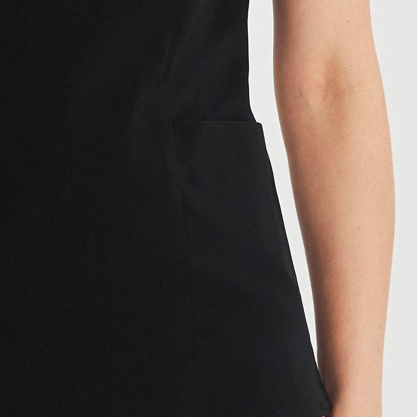Close-up of black front zipper scrub top showing a side patch pocket detail,Black