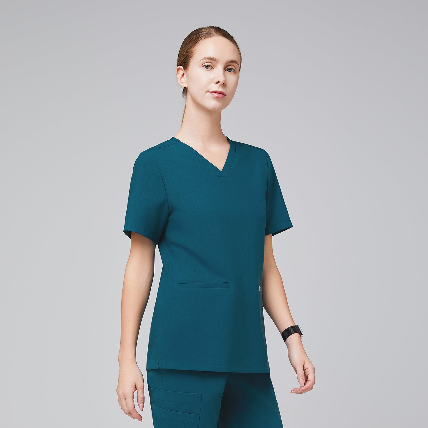 A woman wearing an Ocean Teal Double Pocket Scrub Top with short sleeves,Ocean Teal