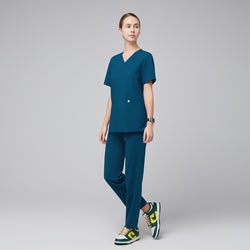 Image of Model wearing an ocean teal double pocket scrub top with matching scrub pants and green-yellow sneakers,Ocean Teal