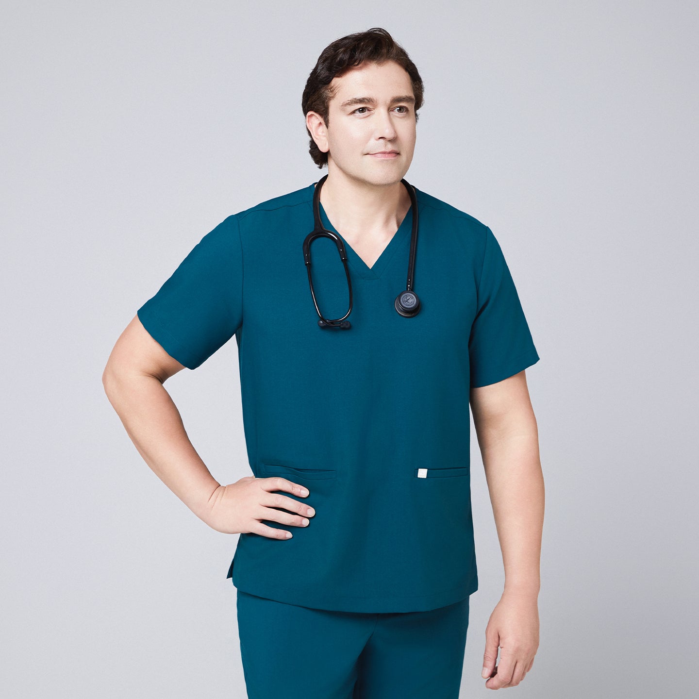 Man in an ocean teal scrub set with a double-pocket V-neck top, wearing a black stethoscope around his neck,Ocean Teal