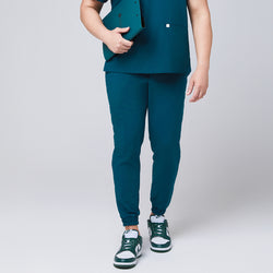 Image of Front view of ocean teal jogger scrub pants with elastic cuffs and a cargo pocket, paired with green and white Nike sneakers,Ocean Teal 