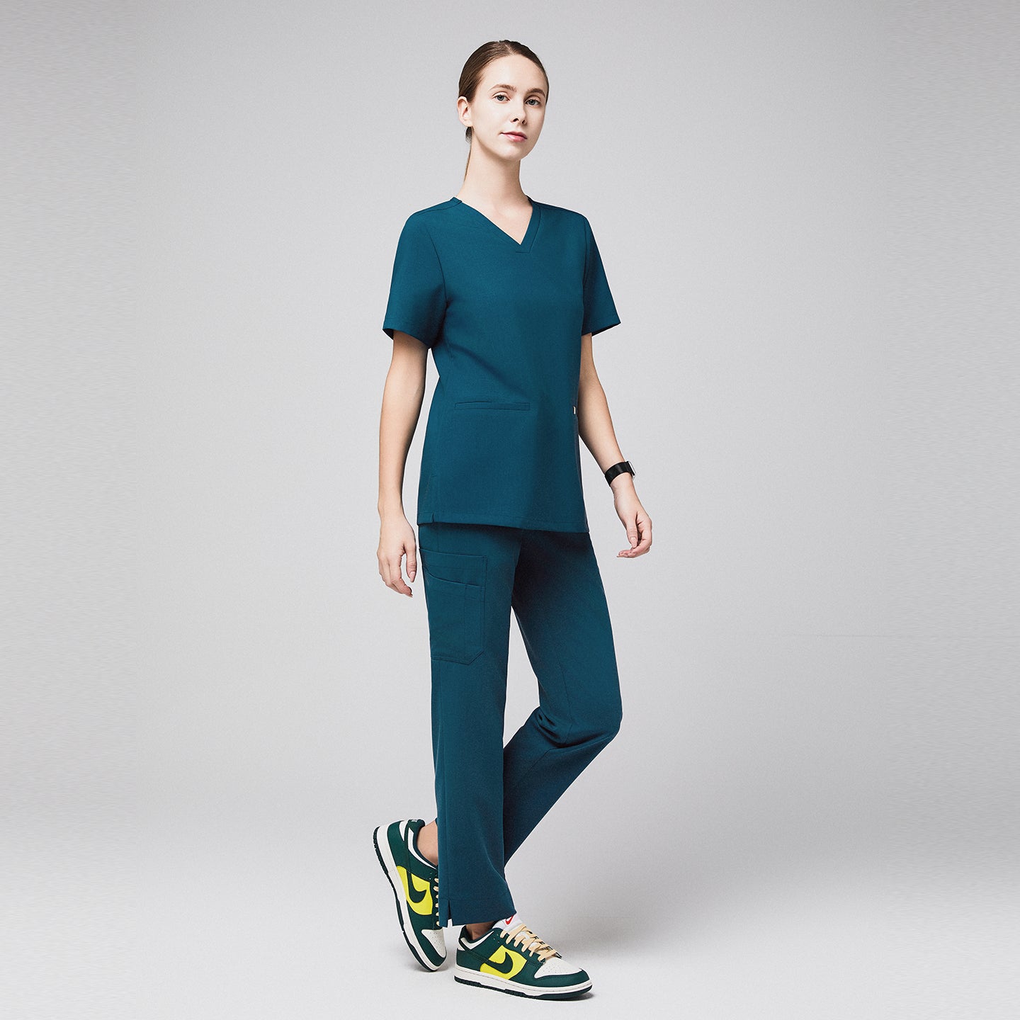 Woman wearing ocean teal scrubs with split hem pants and side pocket, paired with green and yellow sneakers,Ocean Teal