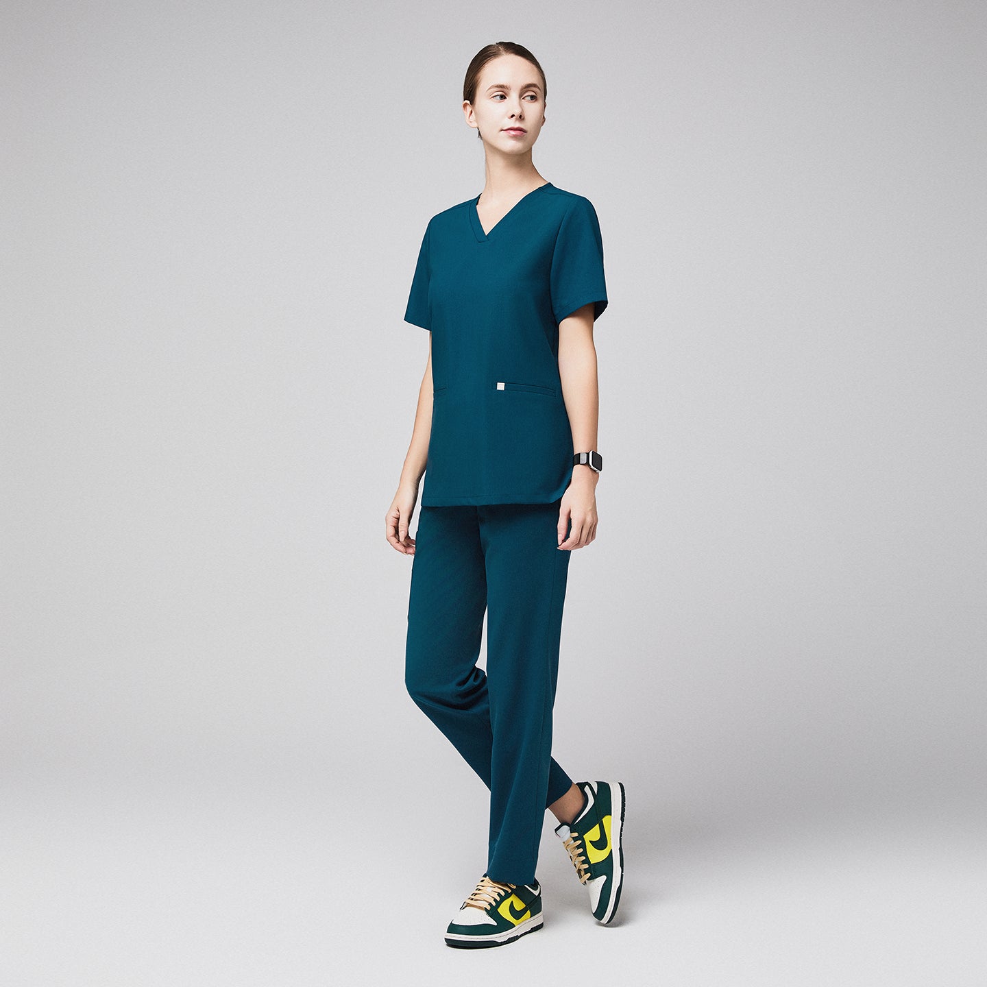 Female healthcare professional in teal scrubs and green sneakers, standing confidently,Ocean Teal