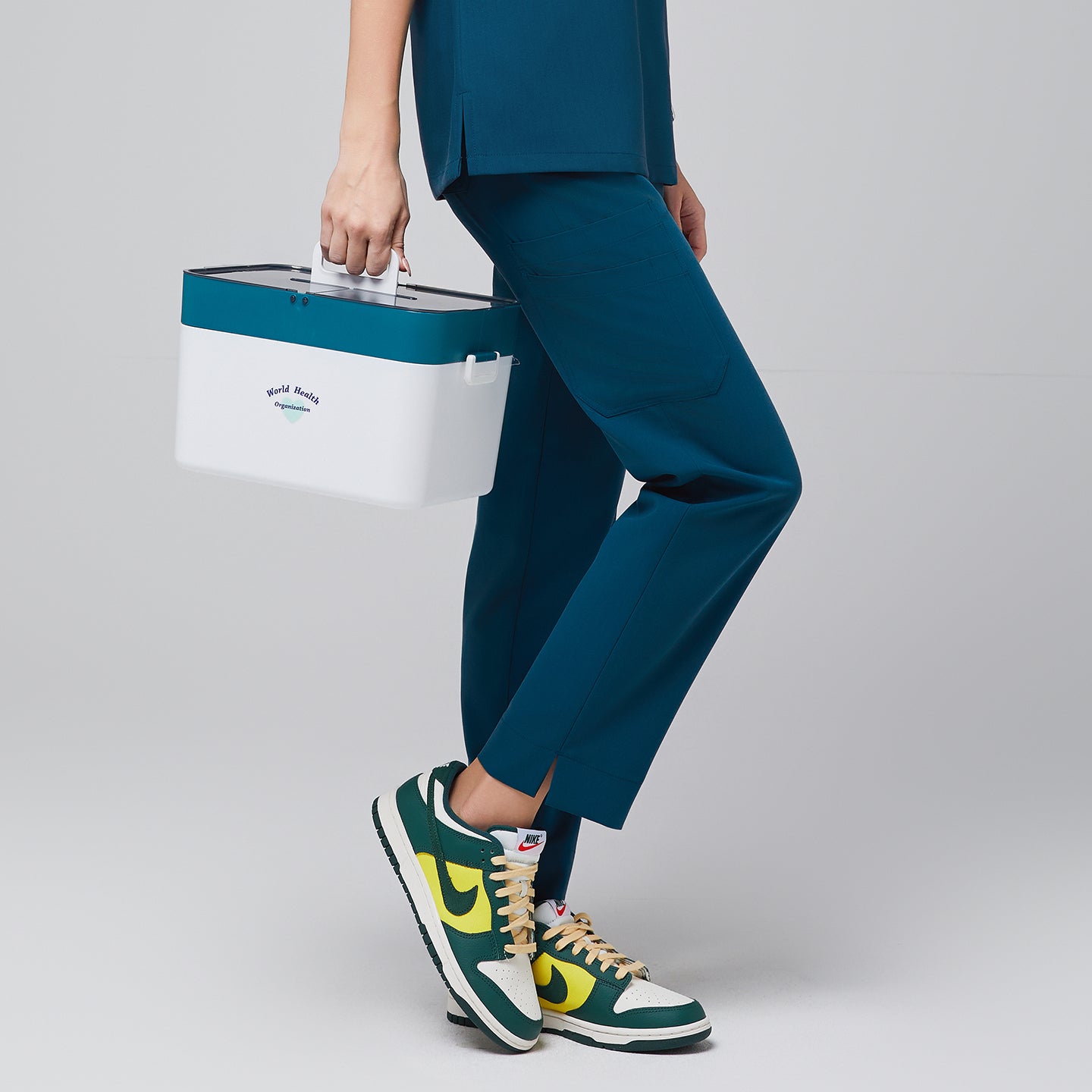 Ocean teal scrub pants with side pocket, paired with green and yellow sneakers, holding a white medical kit,Ocean Teal