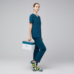 Image of Model wearing ocean teal scrub set with green and yellow sneakers, holding a white medical kit,Ocean Teal