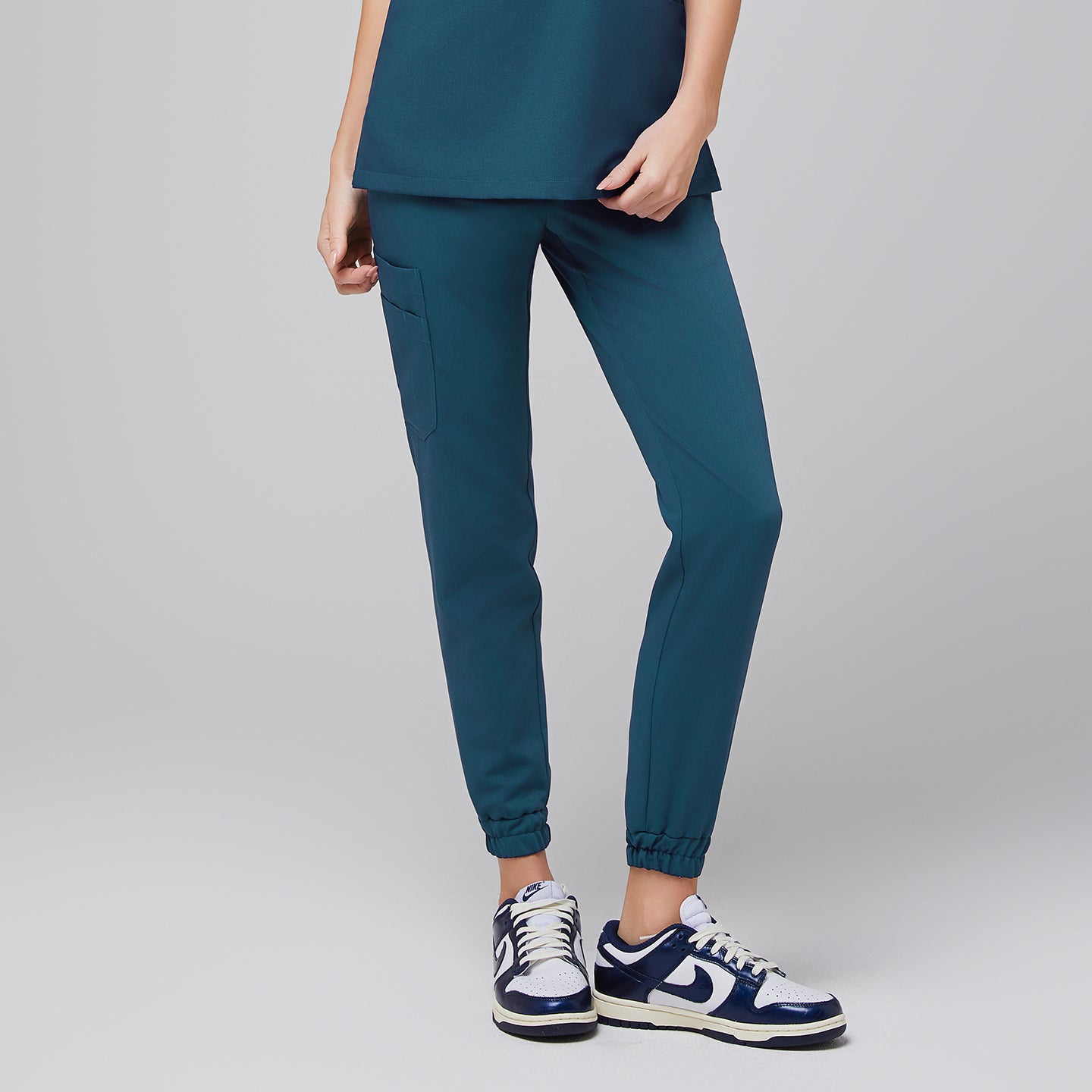 Female wearing teal jogger scrub pants with elastic cuffs and side pockets, paired with navy and white sneakers,Ocean Teal