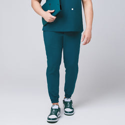 Image of Ocean teal jogger scrub pants made of stretchy fabric and matching ocean teal scrub top, with a teal binder in hand,Ocean teal